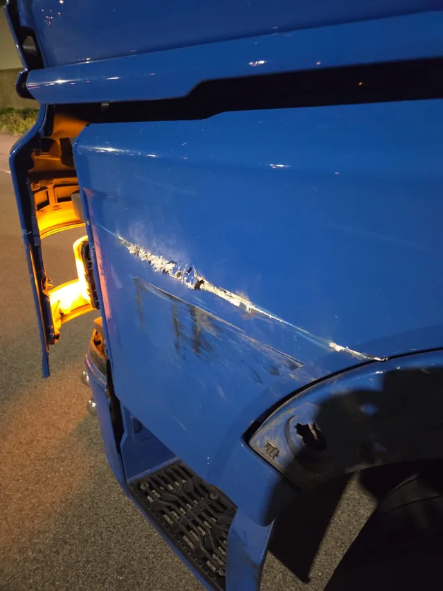 Beschädigung an der Seite eines blauen LKW-Fahrerhauses