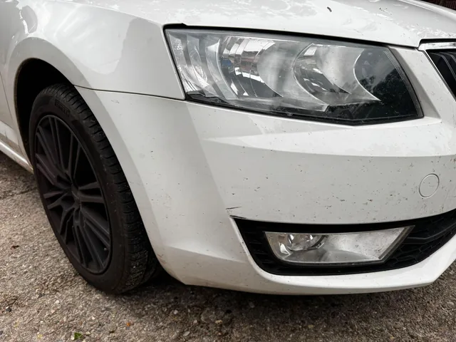 Detailaufnahme der vorderen Stoßstange und des Scheinwerfers eines weißen Skoda